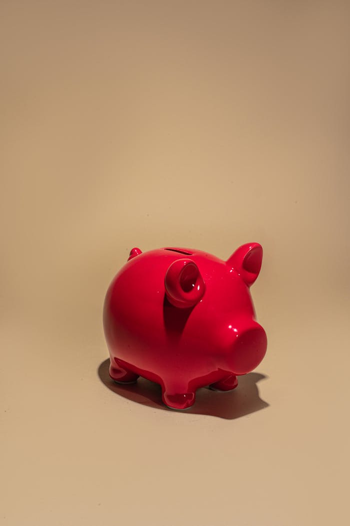 Vibrant red piggy bank on a beige background symbolizing savings and financial security.